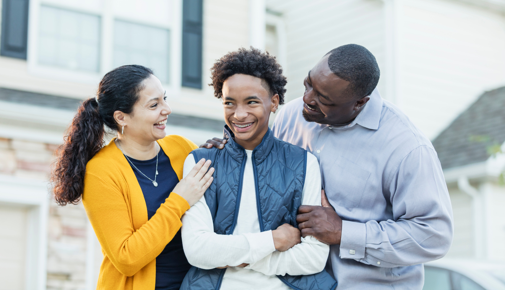 Teenage boy with parents outside home