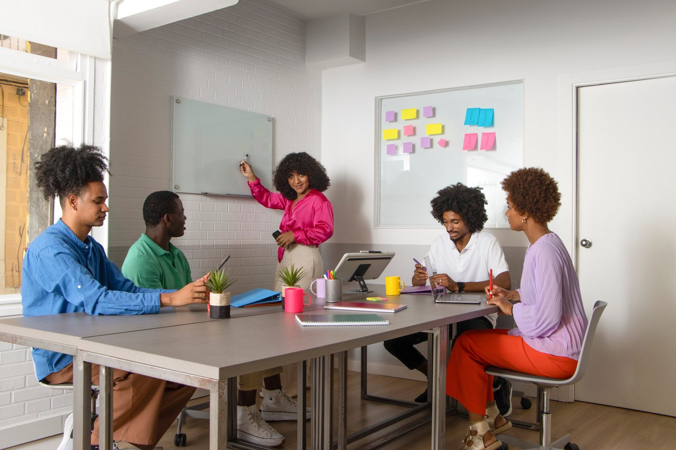 a group of people in colorful sweaters sitting around a table in an office