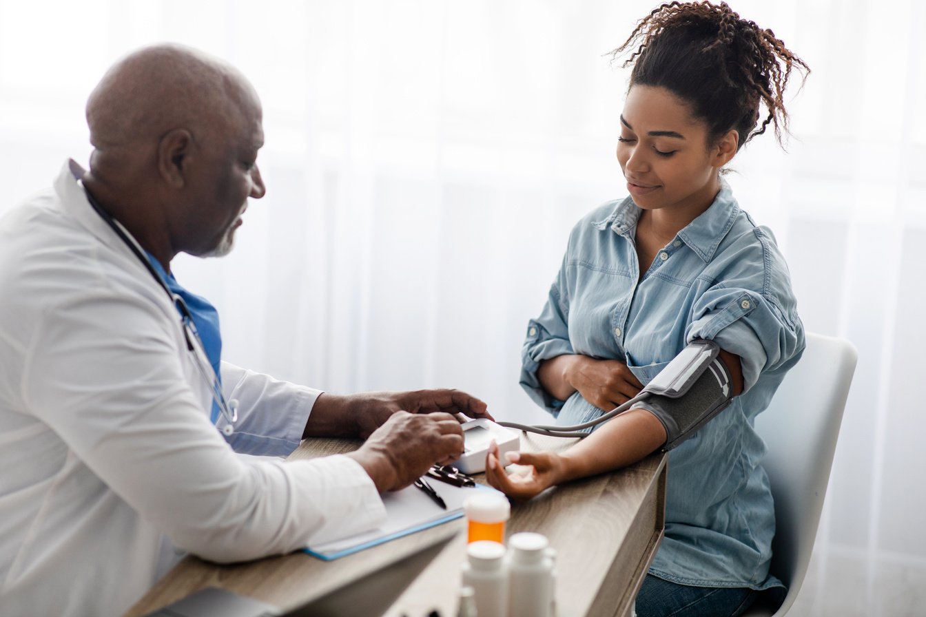 Black doctor checking measuring pressure of pregnant patient